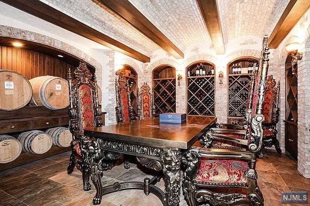 The wine room in this Franklin Lakes, NJ property listed by William Boswell has ornate carved wooden furniture and enough room for both bottle and cask storage is truly fit for a king.