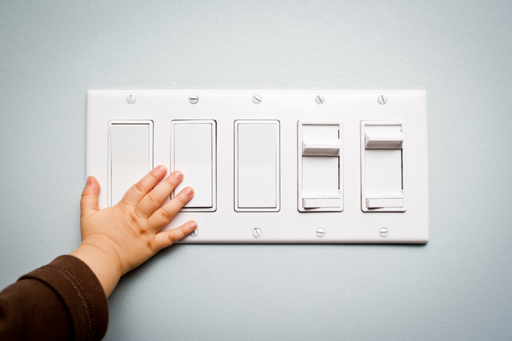 Baby hand touching a panel with five light switches