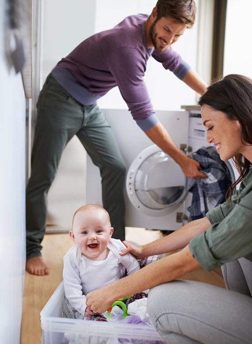 Shot of a young family having fun while doing laundry