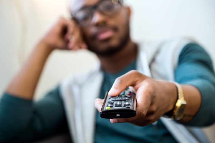 Portrait of handsome young black man watching tv at home.