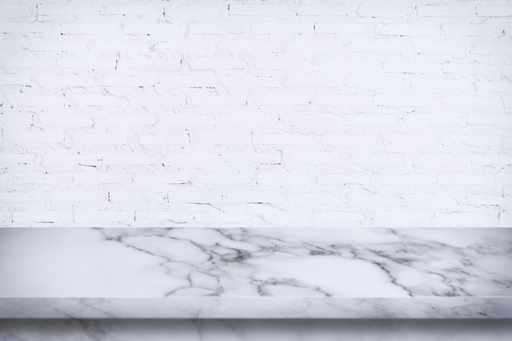 Empty marble table with white brick wall background.