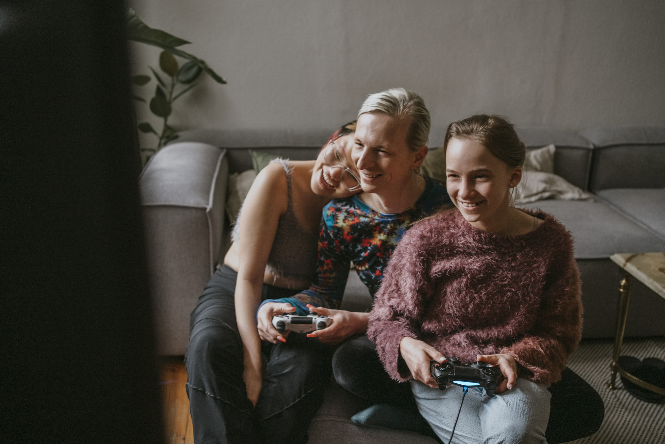 Happy gay couple enjoying while playing video game with daughter at home -  Coldwell Banker Blue Matter