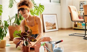 Woman sitting on floor arranging some green plants for healthier air.