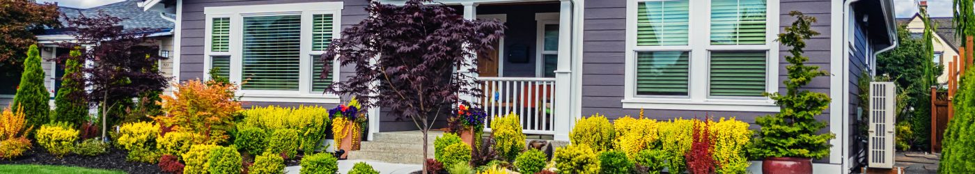 A home for sale in spring with colorful landscaping and a front porch.