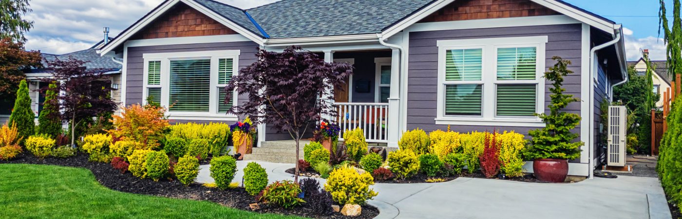 A home for sale in spring with colorful landscaping and a front porch.