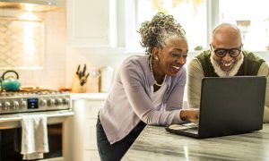 Happy couple looking at laptop together in kitchen