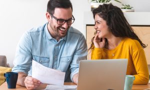 Laughing couple looking for first home online