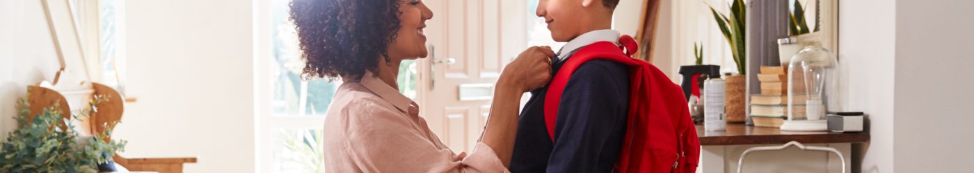 A woman adjusts her child's school uniform near the front door of their new home.